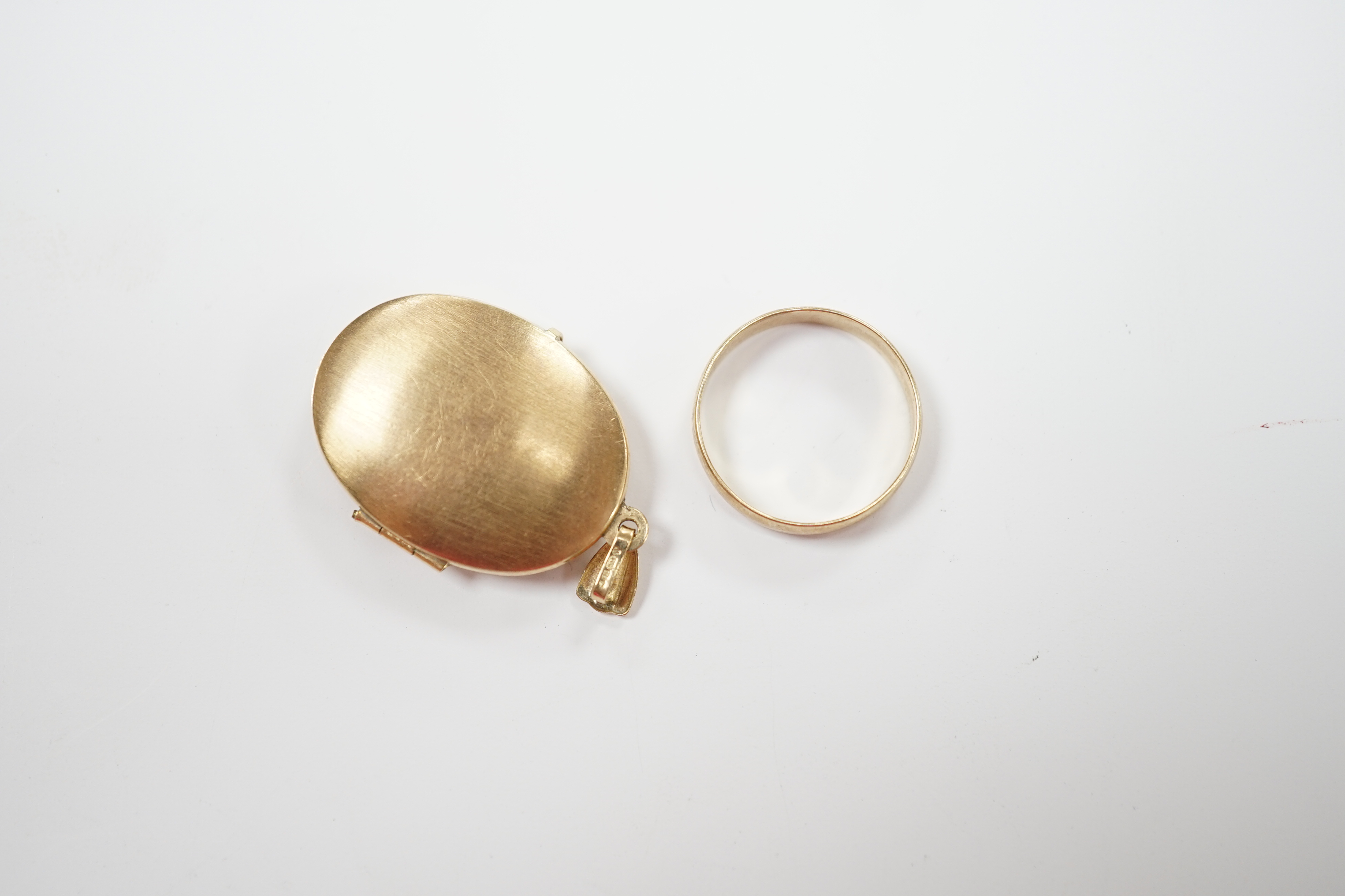 A 9ct gold wedding band and a modern 9ct gold oval locket